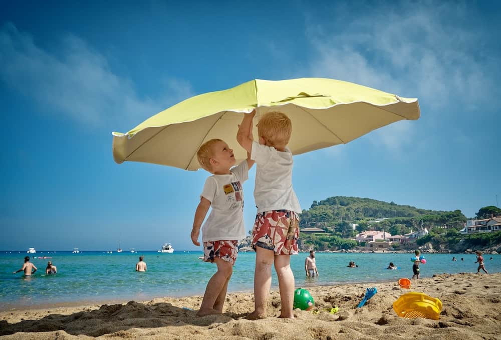 sunburn info - kids underneath umbrella on beach